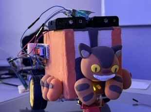 The smart car on a workbench: foam chassis, exposed breadboard and sensor wiring, with a cat figure riding on top